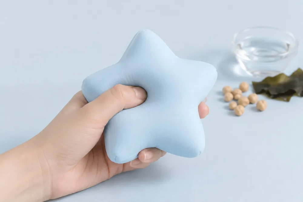 A hand gently squeezing a soft pale blue star squishy